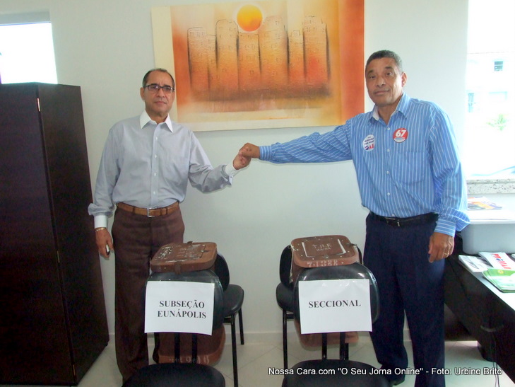 Os candidatos Eliomar Britto (esquerda) e Ap&oacute;stolo (direita) posam pra foto junto das urnas