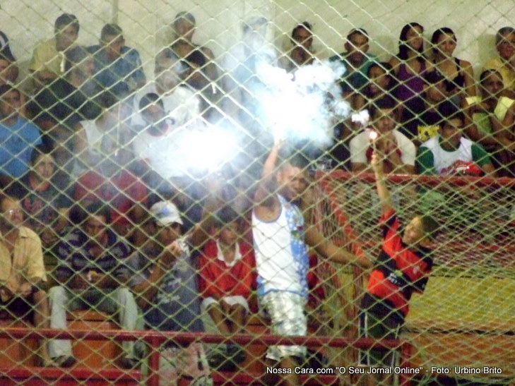 Fogos de artificio sendo queimados na arquibancada durante a partida de futsal