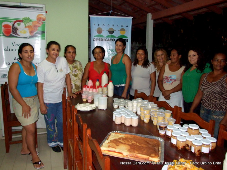 Mesa arrumada com os doces e ao fundo as alunas do curso