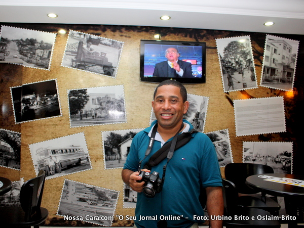 O rep&oacute;rter Oslaim Brito veio de Sampa contratado para cobrir o Pedr&atilde;o 2010 pelo jornal Nossa Cara.com posa em frente a um painel de fotos antigas de Eun&aacute;polis no Bar Colizeu