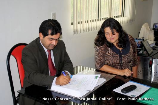 A vereadora Ruthe Contadora observa enquanto e o vereador Valdiran Marques assina um documento