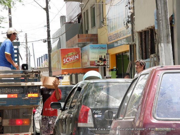 Aqui n&oacute;s vemos o carregador recebendo os tijos para levar pra dentro da obra coordenado pelo gerente ou encarregado que s&oacute; se v&ecirc; a cabe&ccedil;a por cima do teto do carro vermelho