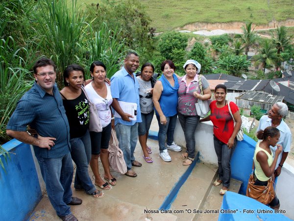 Comitiva da secret&aacute;ria posa para foto com a comunidade ao fundo
