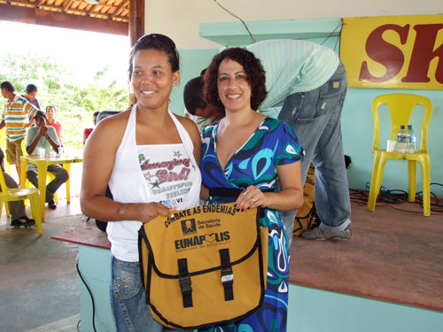A primeira dama Cl&aacute;udia Oliveira (de azul) faz a entrega do mat&eacute;rial a uma agente de endemias