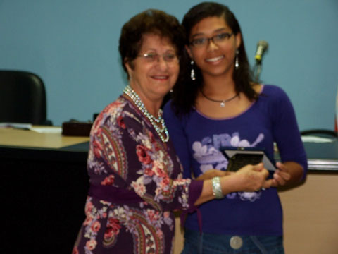 A cantora Gabriela Mirley, sendo homenageada pela professora Nevolanda