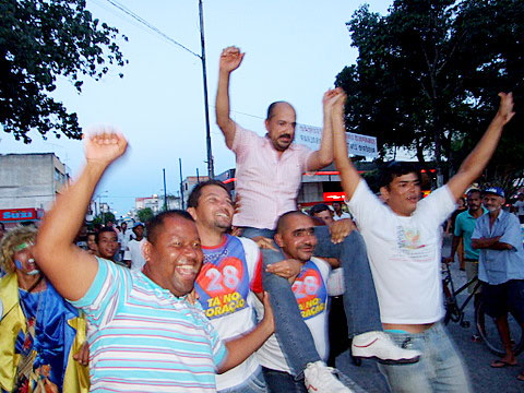 O prefeito Rob&eacute;rio Oliveira &eacute; carregado por correligion&aacute;rios o chegar na Pra&ccedil;a da Bandeira.