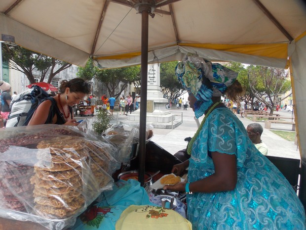 Baiana Mary atendendo a cliente turista na Cruz Ca�da, no Pelourinho. (Foto: Denise Paix�o/G1)